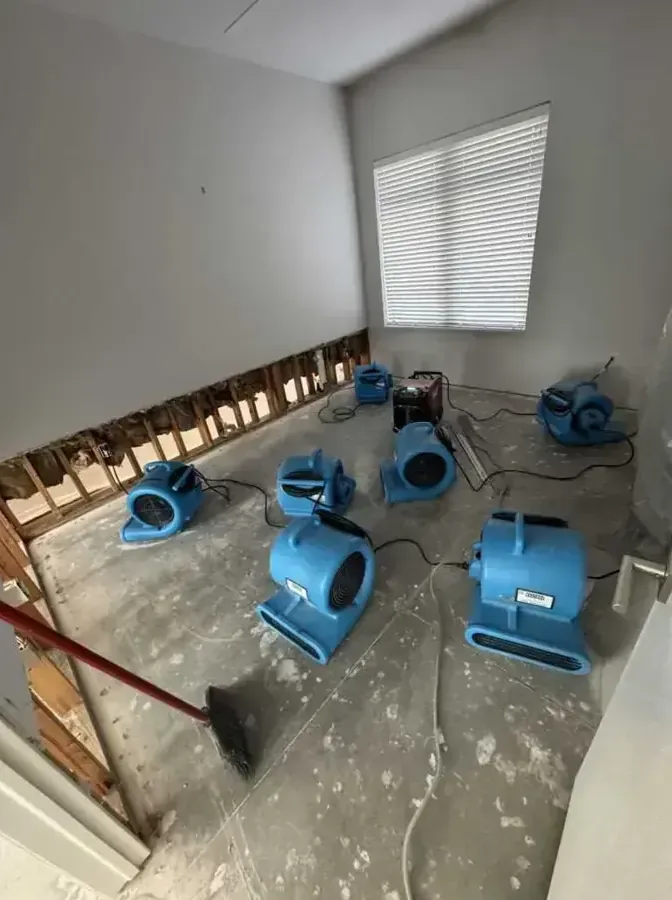 Air movers drying an emptied room after a flood cut along the lower drywall