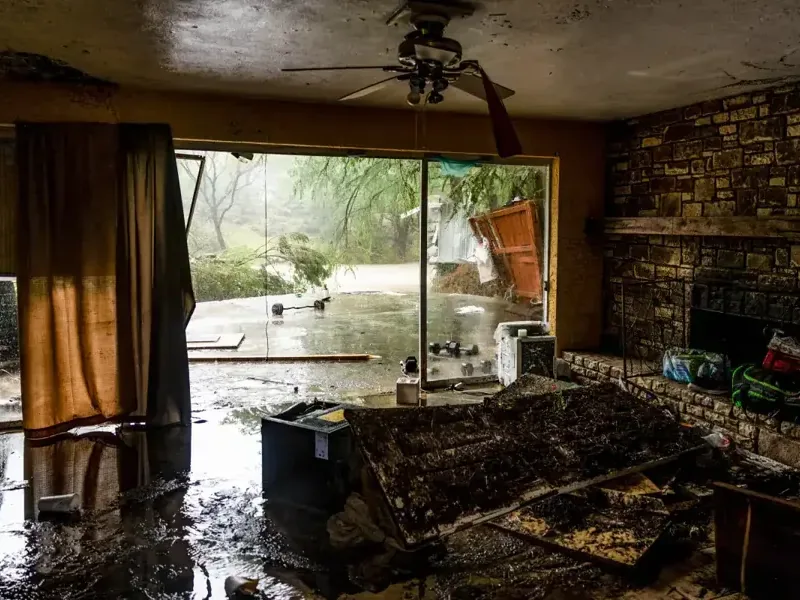 Muddy storm water and debris spread across a living room floor after a flood