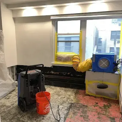 Dehumidifier and air mover running in a room with the flooring removed, a typical Stanwood dry-out setup