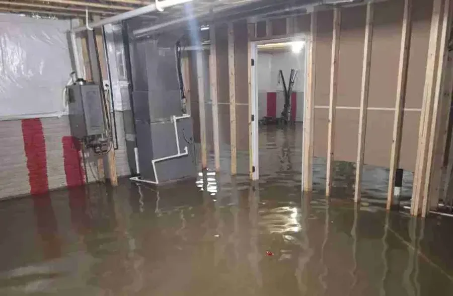 Standing water spread across an unfinished basement floor